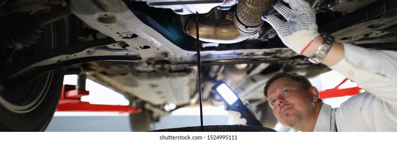 Male Worker Holding In Hands Electric Torch Inspecting Oil Leak Under Car Portrait. Auto Occupation Concept