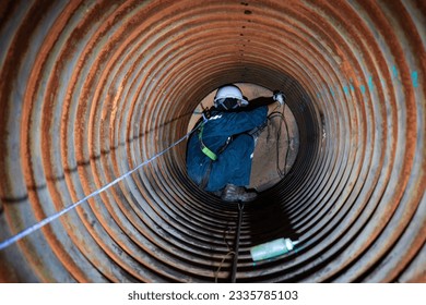 Male worker inspection measured the coil pipe circular thickness of the boiler scan minimum thickness into line rope access symbol dangerous confined space