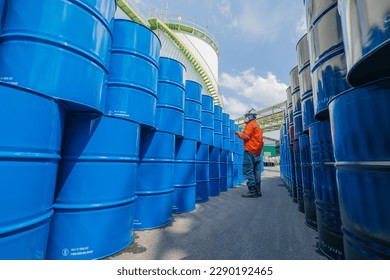 La inspección de los trabajadores masculinos registra barriles de aceite de tambor azul horizontal o químico puestos en la cara media máscara para la industria.