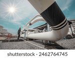 Male worker inspection at steel long pipes and pipe elbow in station oil factory during refinery valve of visual check record pipeline oil and gas industry sunlight