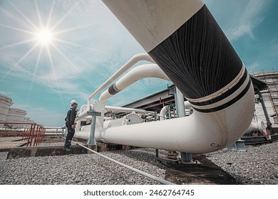 Male worker inspection at steel long pipes and pipe elbow in station oil factory during refinery valve of visual check record pipeline oil and gas industry sunlight - Powered by Shutterstock