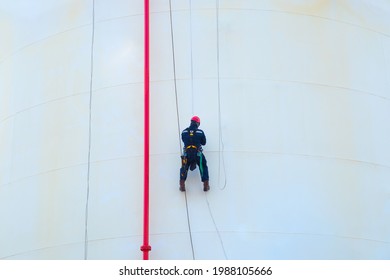 Male Worker Inspects The Walls Of A Chemical Storage Tank With Ropes.