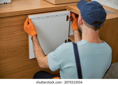 Male worker measuring cupboard door in kitchen