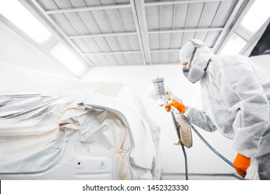 Male Worker Painting A Car In A White Paint Booth.