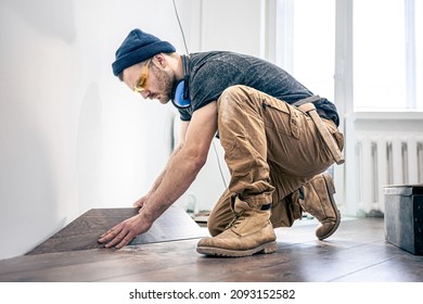 A male worker puts laminate flooring on the floor.