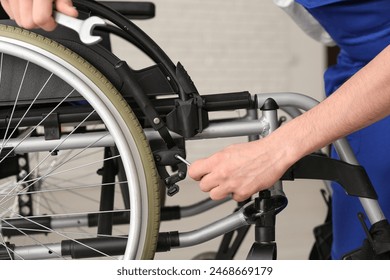 Male worker repairing wheelchair in room, closeup - Powered by Shutterstock