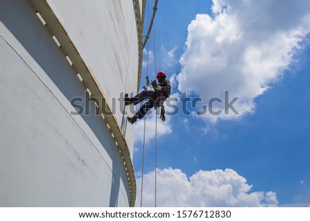 Male worker rope access height safety inspection of thickness storage oil and gas tank industry