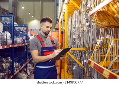 Male worker, salesman or building materials store manager conducts inventory of goods. Young man in overalls writes on clipboard available stock of goods in hardware or construction store. - Shutterstock ID 2143900777