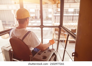 Male worker sitting in operator cabin of overhead crane