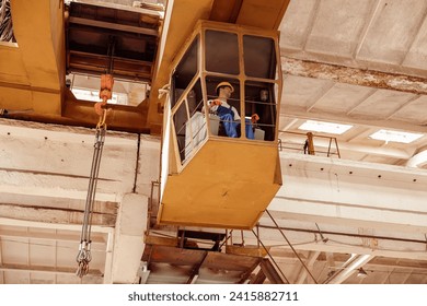 Male worker sitting in operator cabin of overhead crane - Powered by Shutterstock