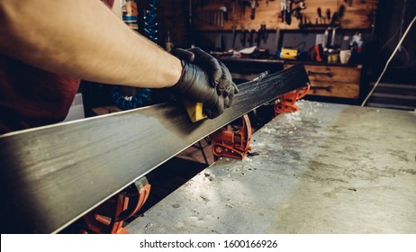 Male worker of ski service workshop doing sharpening and repair of skis. Sharpening ski edges with a manual side-edge tuning tool fitted with a diamond stone. Theme repair of ski curb.