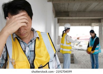 Male worker stands stressed, anxious unhappy after being punished and criticized by an architect foreman with female colleague on a construction site being punished disciplinary. - Shutterstock ID 2192704599