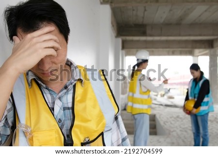 Male worker stands stressed, anxious unhappy after being punished and criticized by an architect foreman with female colleague on a construction site being punished disciplinary.