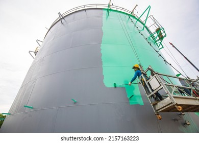 The male worker takes the cable car holding an industrial painting brush used for shell plate tank oil surface surface green color coating. - Shutterstock ID 2157163223
