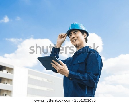 A male worker using a tablet PC in front of a building