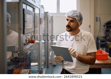 Male worker using touchpad during quality control inspection in a factory plant.