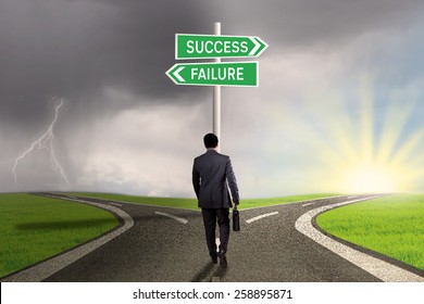 Male worker walking on the road and find two signpost with two choices to success or failure