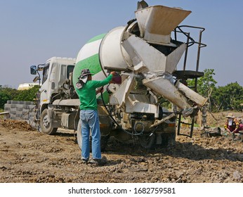 A Male Worker Washing / Cleaning A Cement Mixer Truck After Finish Pouring Out The Concrete 