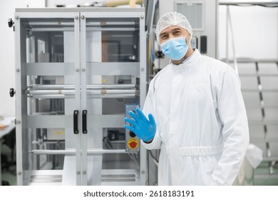The male worker waves while dressed in cleanroom attire, showcasing the importance of safety and hygiene in the workspace.