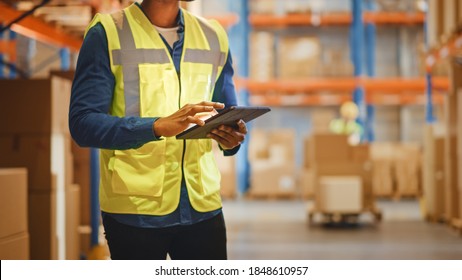 Male Worker Wearing Hard Hat Checks Products Stock and Inventory with Digital Tablet Standing in Retail Warehouse full of Shelves with Goods. Distribution, Logistics. Close-up Shot. - Powered by Shutterstock