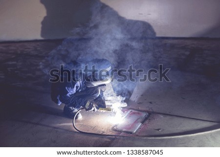 Male  worker wearing protective clothing repair  bottom plate storage tank industrial construction smoke inside confined spaces.