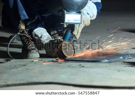 Male  worker wearing protective clothing repair grinding bottom plate storage tank industrial construction inside confined spaces.