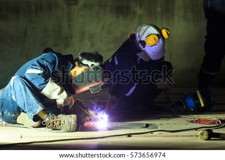 Male  worker wearing protective clothing repair  bottom plate storage tank industrial construction smoke spotlight inside confined spaces.