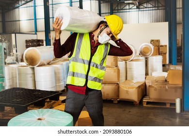 
Male workers carry heavy rolls of fabric over their shoulders to move them into production and are at risk of injury from lifting too heavy loads many times without weight-lifting equipment. - Shutterstock ID 2093880106