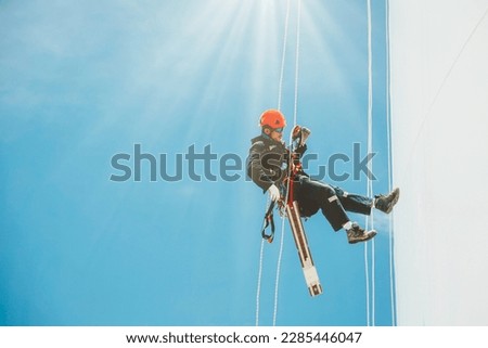 Male workers down height tank rope access inspection of thickness shell plate storage tank gas propane safety work at height 
sunlight shines afternoon.