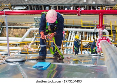 Male workers rope access height safety connecting with a knot safety harness, clipping into roof fall arrest and fall restraint anchor point systems ready to ascending, construction site oil tank dome - Shutterstock ID 1973104403