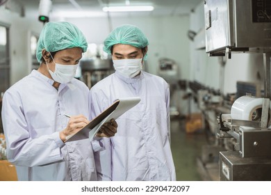 Male workers working together in drinks beverage factory with hygiene clean safety. worker check product quality process. - Powered by Shutterstock