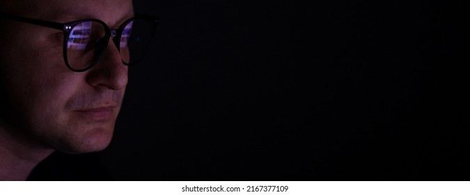 Male Working Online Late. Close Up Side View Of Focused Man Wears Computer Glasses For Reducing Eye Strain Blurred Vision Looking At Pc Screen With Computer Reflection Using Internet, Watching.