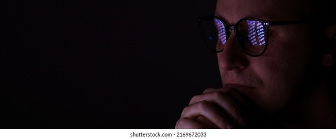 Male Working Online Late. Close Up Side View Of Focused Man Wears Computer Glasses For Reducing Eye Strain Blurred Vision Looking At Pc Screen With Computer Reflection Using Internet, Watching.