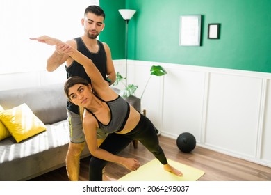 Male Yoga Instructor Helping A Fit Young Woman To Do A Side Angle Pose 