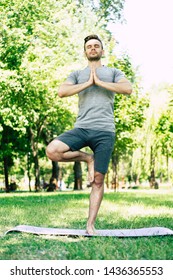 Male Yoga Relaxation. Sporty And Slim Handsome Young Man Is Doing Yoga Exercises In City Park Outdoors. Healthy Lifestyle And Strong Soul And Body