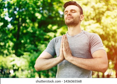 Male yoga relaxation. Sporty and slim handsome young man is doing yoga exercises in city park outdoors. Healthy lifestyle and strong soul and body