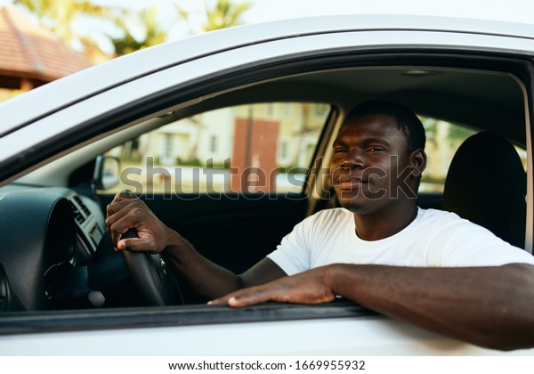 male young african american in car in white\
t-shirt on the street