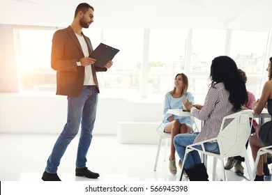 Male young moderator of business workshop meeting with successful startuppers explain concept of conversation and interview with students and guests before beginning in modern coworking space - Shutterstock ID 566945398