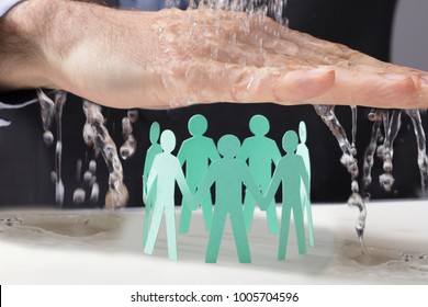 Male's Hand Protecting The Green Paper Cutout Human Figures In Circle From Falling Water - Powered by Shutterstock