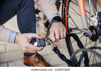 Male's hands locking up bicycle outdoors. - Shutterstock ID 2150073647