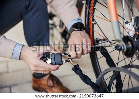 Male's hands locking up bicycle outdoors.