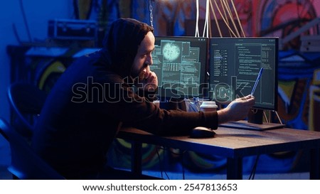 Malicious man hacking and talking on phone with partner, stealing credit card numbers, manipulating banking systems. Evil hacker runs dangerous code, chatting with friend in telephone call, camera B