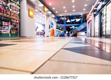 In the mall. Multi-colored illuminated signs. Glass shop windows. Product selection. Go shopping. Focus on the floor. Close up view from the level of the floor tiles. - Shutterstock ID 2128677317