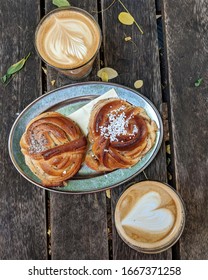 Malmo, Sweden - 29 August 2019: Overhead View Of A Cinnamon Bun, Cardamom Bun, And Lattes On A Picnic Table On The Patio Of Lilla Kafferosteriet, A Cafe.