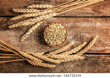 Malt in small bowl and spikes on wooden background