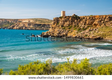 Malta. Ghajn Tuffieha Tower on cliff by the sea bay. Maltese landscape with clear blue sky.
