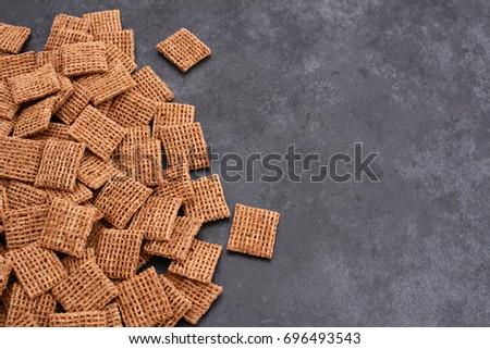 Malted shredded wheat biscuits breakfast cereal in a border line with copy space on a dark grey slate tile background