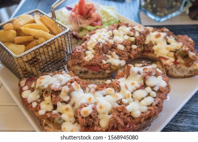 Maltese Bread (Hobz Biz-Zejt) topped with a mix of tuna, olives and cheese and with a side of fries. - Shutterstock ID 1568945080
