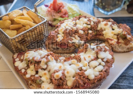 Maltese Bread (Hobz Biz-Zejt) topped with a mix of tuna, olives and cheese and with a side of fries.