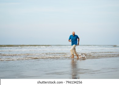 Maltese Dog And Owner Running In The Water At The Beach